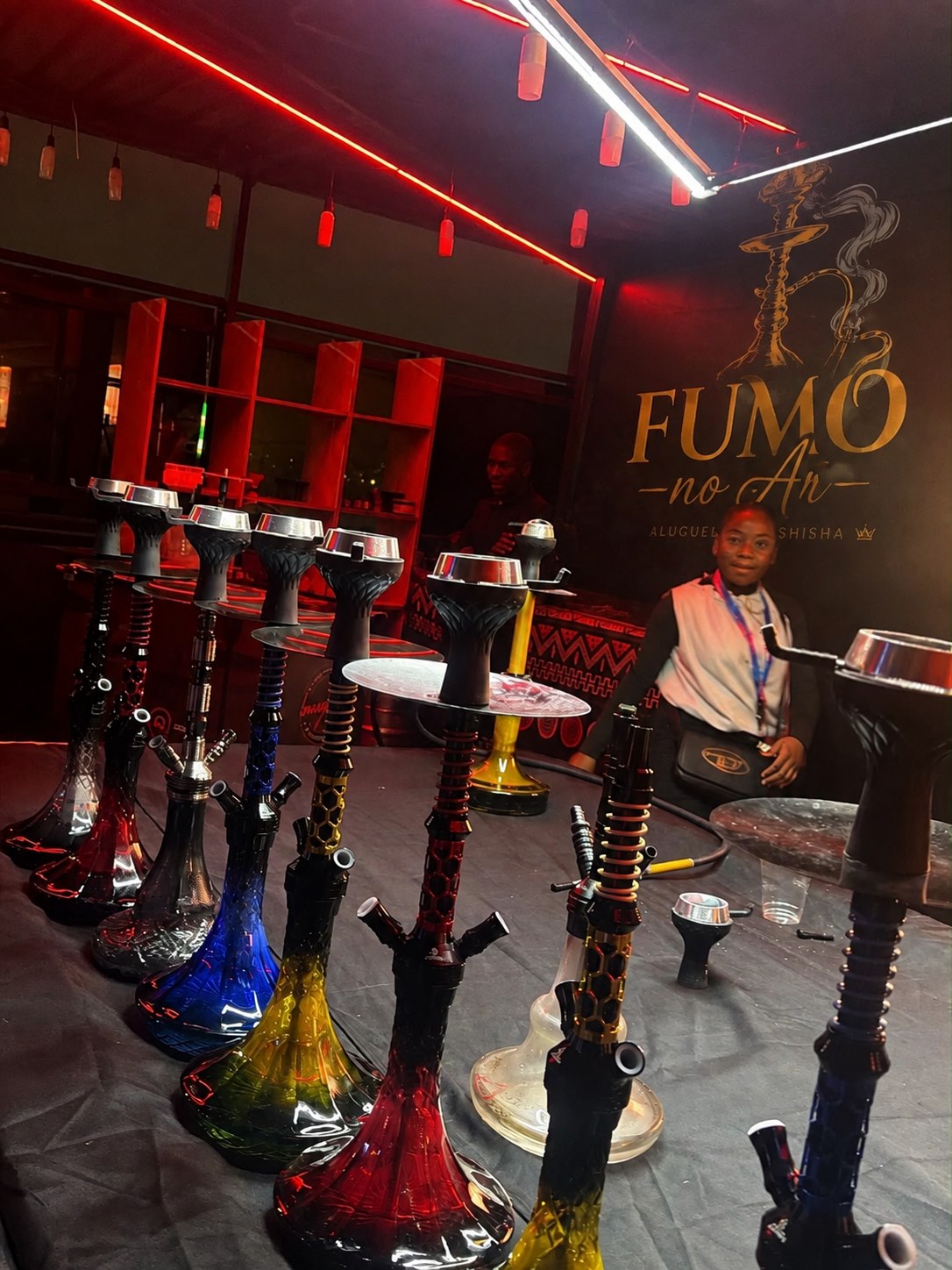 Lounge Fumo no Ar com shishas, luzes vermelhas e ambiente preparado para convívio